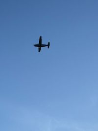 Low angle view of airplane against clear blue sky