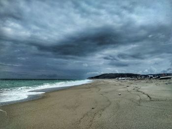 Scenic view of beach against cloudy sky