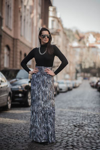 Fashionable woman standing on footpath in city