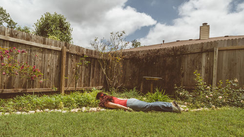 Man lying down on land against sky