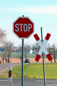 Road sign by street against sky in city