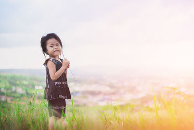 Portrait of boy standing on field against sky