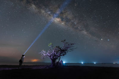 Man flashing light against sky at night