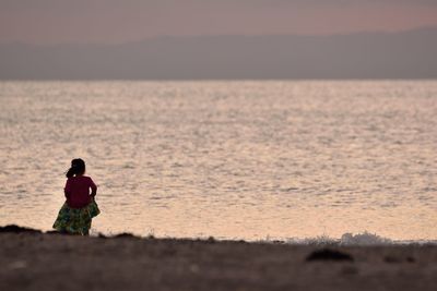 Rear view of girl standing at beach