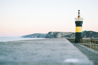 Lighthouse by sea against clear sky