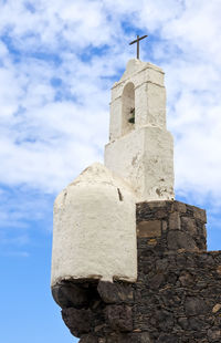 Low angle view of cross on building against sky