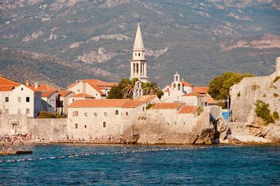 Buildings by sea against mountain