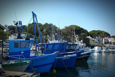 Boats moored at harbor against clear sky