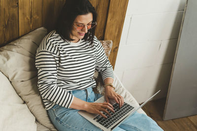 Beautiful woman is sitting at home and working on a laptop.