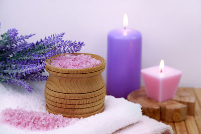 Candles with salts and flowers by towel on table