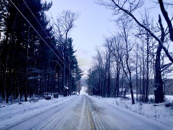 Road amidst snow covered trees against sky