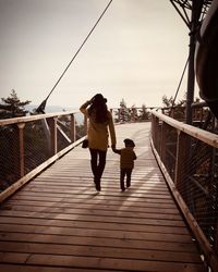 Rear view of people walking on footbridge