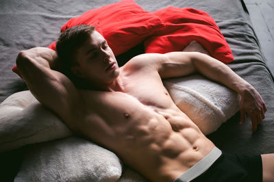 High angle view of shirtless man lying on bed at home