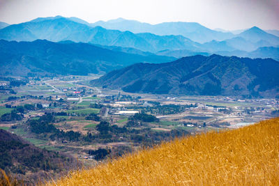 Scenic view of agricultural field by mountains against sky
