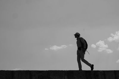 Side view of boy walking against sky