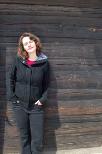 Portrait of smiling young woman standing against wall