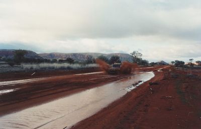 Road passing through landscape against cloudy sky