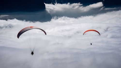 People paragliding in cloudy sky