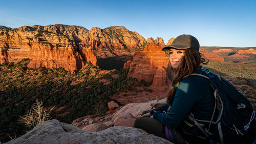 Side view of woman on rock against sky