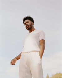 Low angle view of young man looking away against sky