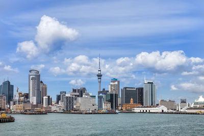 Sea by modern buildings against sky in city