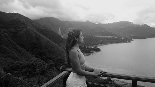 Side view of woman looking at mountains against sky