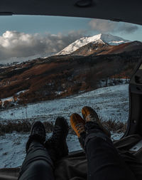 Low section of people in car against mountains and sky