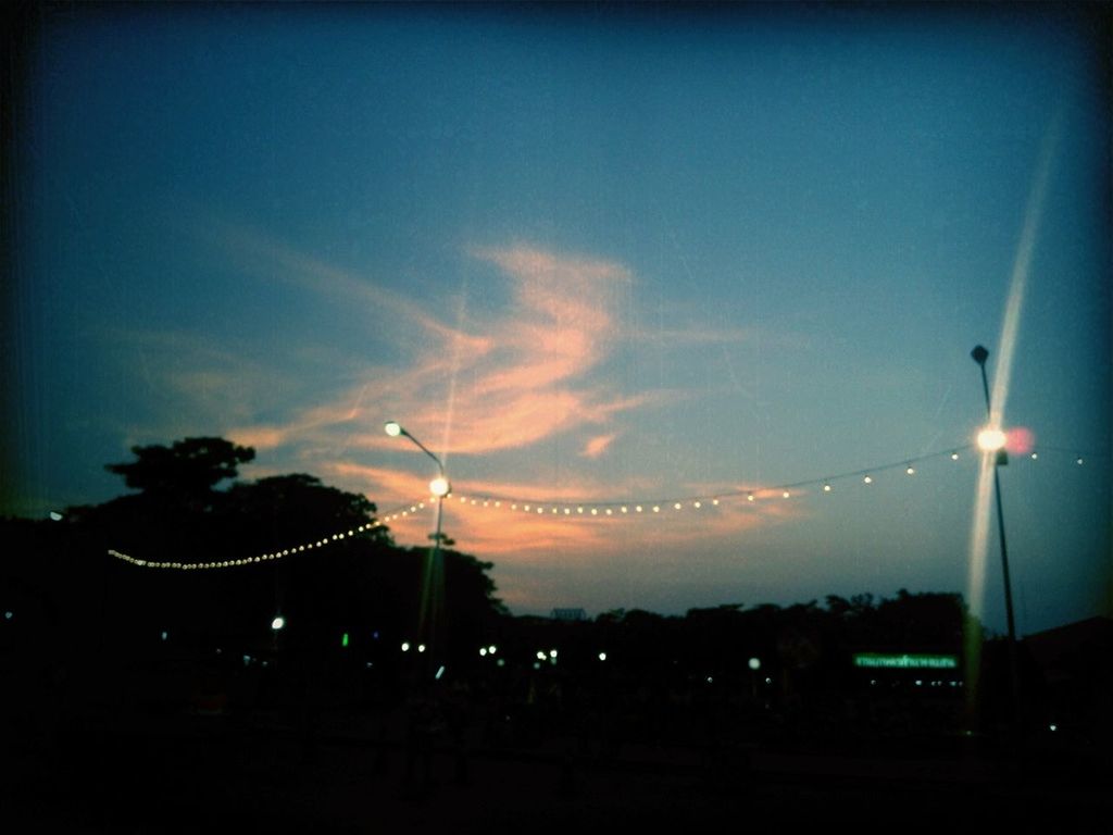 illuminated, night, sky, street light, low angle view, long exposure, lighting equipment, electricity, motion, dusk, light trail, transportation, light - natural phenomenon, outdoors, road, arts culture and entertainment, blurred motion, silhouette, cloud - sky, no people