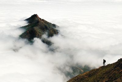 Man standing on mountain against cloudscape