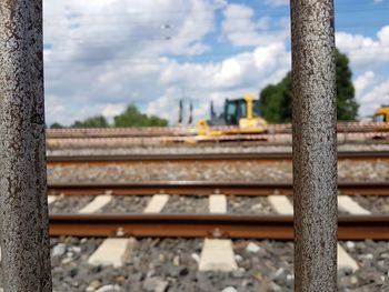 Railroad tracks against sky seen through fence