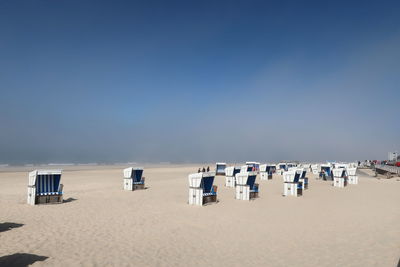 Hooded chairs on beach against clear sky