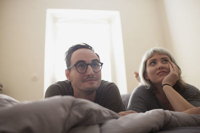 Young couple lying on bed watching tv