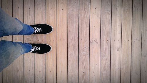 Low section of man standing on boardwalk