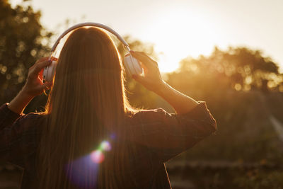 Rear view of woman standing against sky during sunset