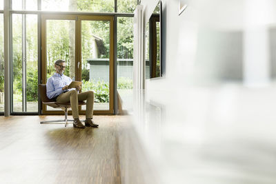 Man sitting on chair in his living room using tablet