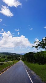 Empty road amidst field against sky