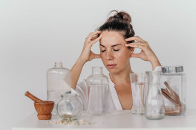 Portrait of a young girl with transparent vessels on a white table