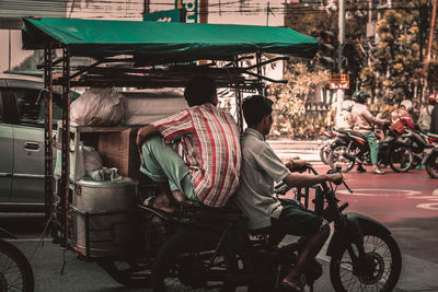 Rear view of people riding motorcycle on road