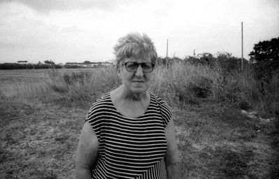 Portrait of woman standing on field against sky