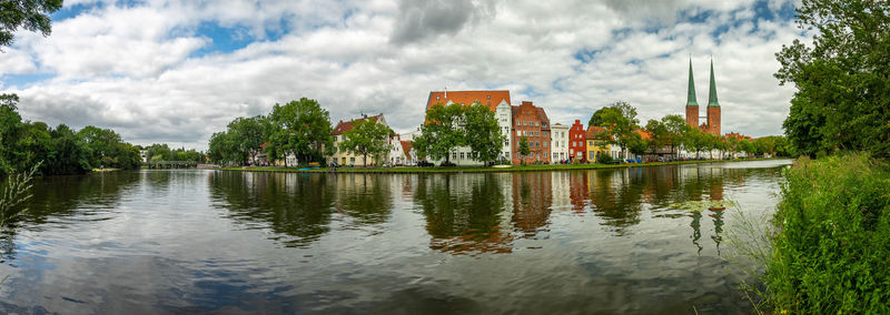 Panoramic view of buildings on riverside against cloudy sky