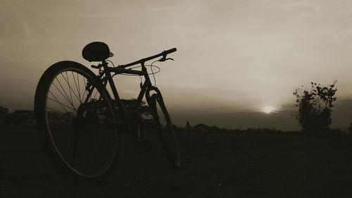 Bicycle on field against sky during sunset