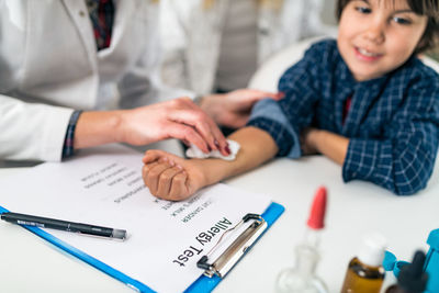 Close-up of doctor performing immunology therapy on hand of boy 