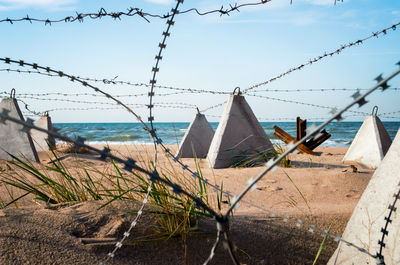 Close-up of fence by sea against sky