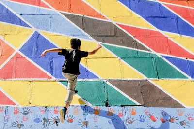 Rear view of boy jumping on colorful wall