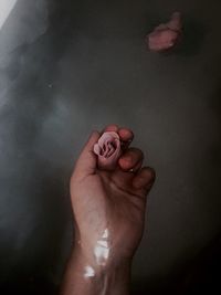 Cropped hand holding rose in bathtub