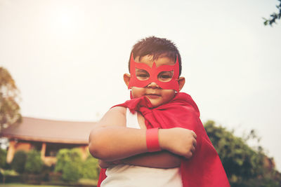 Boy with cape and eye patch playing in park