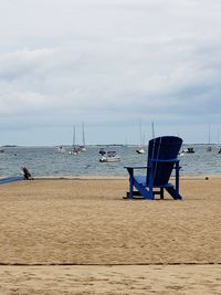 Deck chairs on beach against sky
