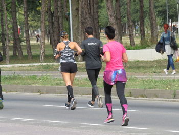 Rear view of people running on road