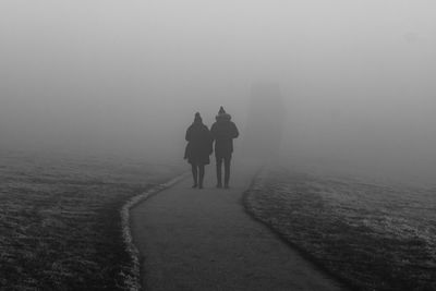 Rear view of people walking on road during winter