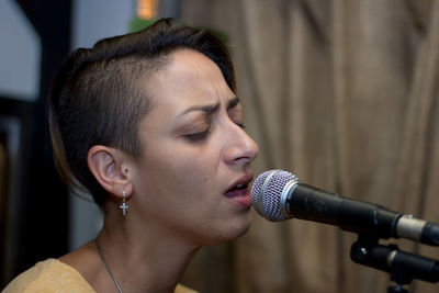 Close-up of woman with eyes closed and short hair singing in microphone